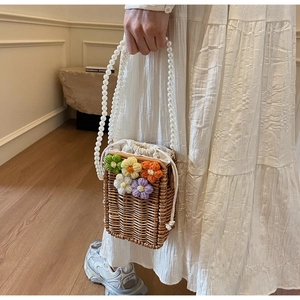Détail du sac seau en paille fait main avec crochet floral et bandoulière perlée