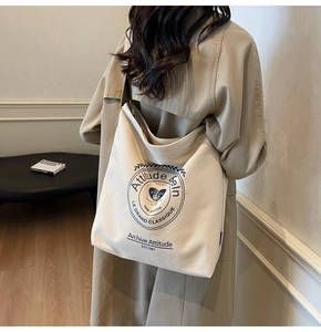 Vue arrière d'une personne portant un sac cabas en toile beige avec logo rétro circulaire