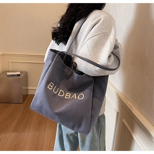 Detail of BUDBAO canvas tote bag showing thick blue fabric and white embroidery