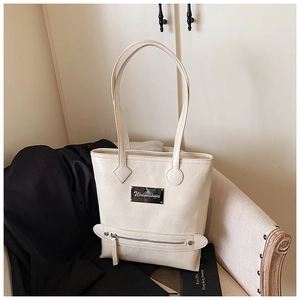 Detailed close-up of cream white tote bag with textured faux leather and metal brand plate