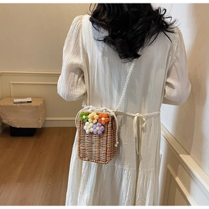 Détail du sac seau en paille avec fleurs au crochet et bandoulière en perles chic