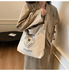 Détail du sac seau en toile blanc cassé avec logo bleu vintage et bandoulière large