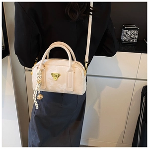 Détail du sac Boston crème avec logo triangle doré et accessoire foulard en soie élégant