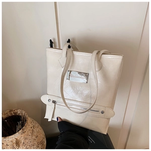 Detailed close-up of cream tote bag with unique wrinkled leather texture and silver buckle