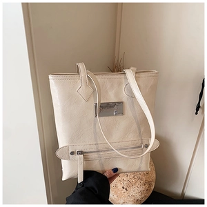 Close-up of cream textured leather tote bag with metallic logo and zipper pocket detail