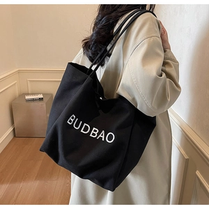 Close-up of black canvas tote bag with white BUDBAO lettering on a long shoulder strap