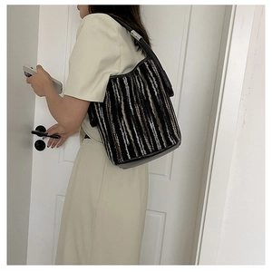 Detail of multi-color woven striped bucket bag with black leather strap and silver clasp