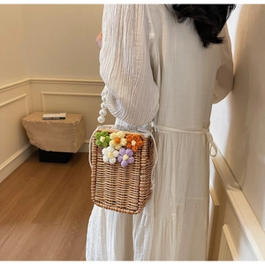 Détail du sac seau en paille tissée avec fleurs au crochet et poignée en perles