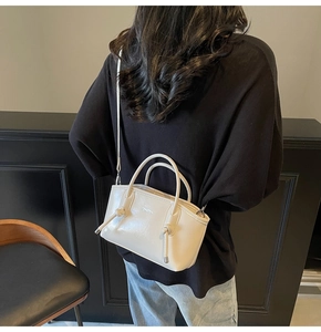 Dettaglio borsa a mano color crema in pelle sintetica con nodi su sfondo abito nero