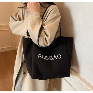Close-up of black canvas tote bag with white BUDBAO print and durable shoulder strap