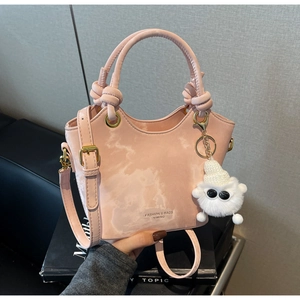 Detail der rosa Beuteltasche mit Knotengriff, Metallösen und Plüsch-Anhänger