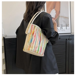 Detail of colorful striped woven tote bag with creamy white leather trim and straps