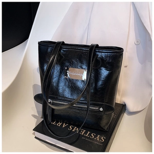 Detail of black oil wax leather tote bag with metallic logo and vintage wrinkled texture