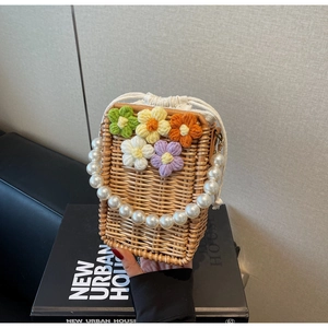 Détail du sac seau en paille tissé avec fleurs au crochet 3D et poignée en perles