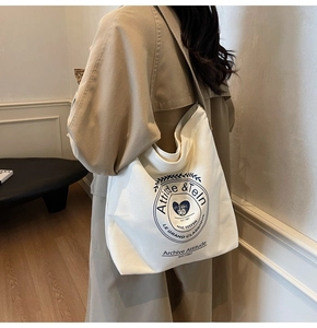 Détail du sac cabas en toile blanche avec emblème bleu vintage et large bandoulière