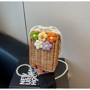 Détail du sac en paille tressée avec fleurs au crochet et bandoulière en perles