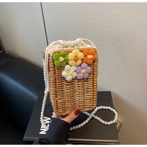 Détail de sac en paille tissé avec motifs floraux colorés et bandoulière en perles