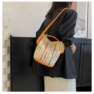 Detailed view of striped crochet bucket bag featuring vibrant orange leather handles