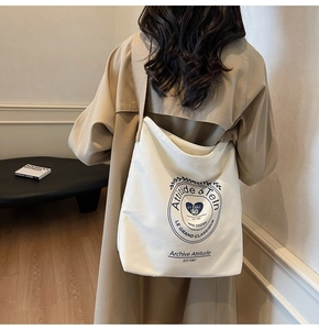 Grand sac cabas en toile blanche avec imprimé vintage porté avec un trench-coat beige