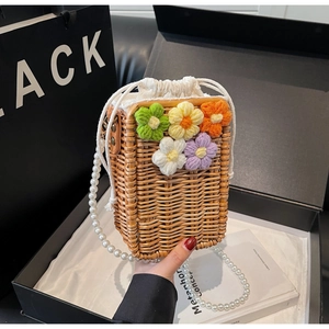 Détail du sac en paille tissée avec fleurs au crochet et bandoulière en perles blanches