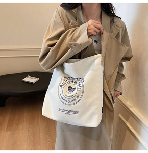 Détail du sac fourre-tout en toile blanc cassé avec logo vintage bleu et étiquette latérale