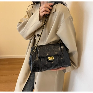 Detailed view of the black quilted leather bag featuring a gold-tone chain and twist lock