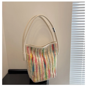 Detail of colorful woven stripes and silver-tone hardware on the cream bucket bag
