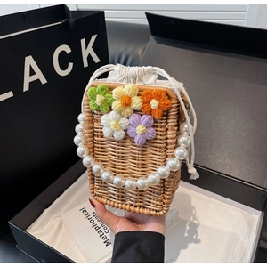 Détail du sac seau en paille tissée avec fleurs au crochet et poignée en perles