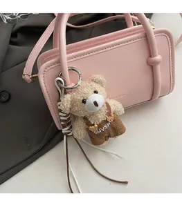 Detail of pink faux leather crossbody bag with cute beige bear plush keychain charm