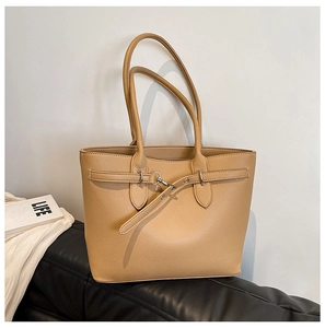 Détail du sac cabas en cuir litchi kaki avec boucle argentée sur un canapé noir
