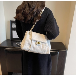 Detailed close-up of white quilted chain bag featuring a gold metal twist lock