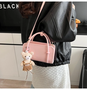 Detail of pink faux leather crossbody bag with cute plush bear charm and sturdy handles