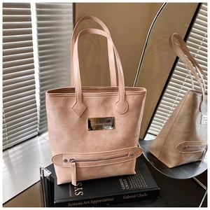 Close-up of pink faux leather tote bag showing metallic logo and zipper detail