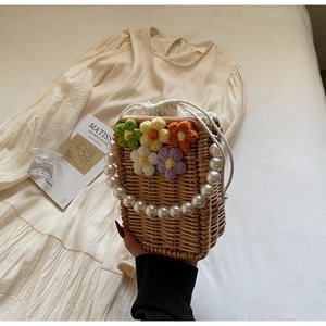 Détails de ce sac seau en paille fait main avec fleurs au crochet et anse perlée