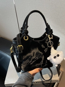 Elegante schwarze Samt-Beuteltasche mit Gold-Hardware und Plüsch-Anhänger-Detail