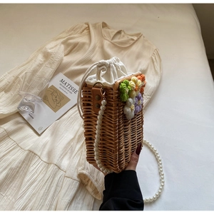 Détail du sac seau en paille avec fleurs au crochet et bandoulière en perles