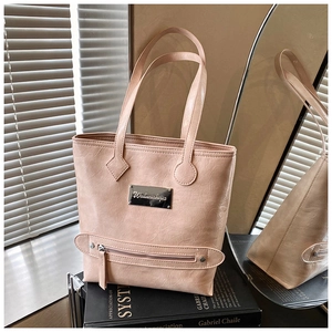 Detail of pink crinkled leather tote bag featuring a metal logo and smooth zipper texture