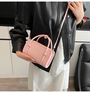 Close-up of pink mini crossbody bag with CLEAREK logo and round handles on a model