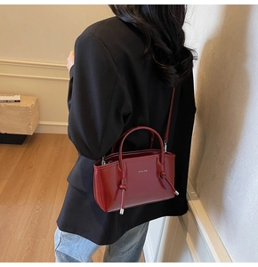 Dettaglio borsa tote in pelle rosso scuro con manici a nodo e logo del marchio