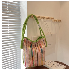 Detail of colorful striped woven bucket bag featuring green leather handles and texture