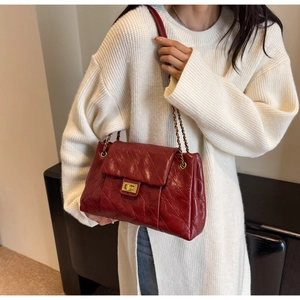 Detail view of dark red quilted chain bag styled with a white knit outfit for women