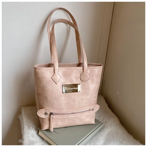 Détail du cabas rose clair avec texture cuir premium et plaque métallique argentée