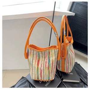 Close-up of colorful striped fabric texture and orange PU handle on the bucket bag