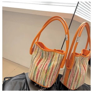Detail of colorful striped woven tote bag with orange leather handles and metal hardware