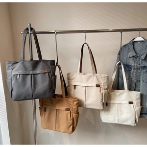 Detailed row of versatile canvas tote bags in four neutral colors with large front pockets