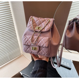 Macro shot of quilted pink backpack with gold chain straps and metal twist lock