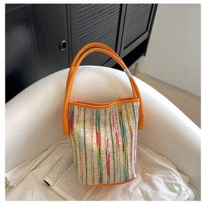 Detail of colorful woven stripes and orange handle on a stylish bucket bag
