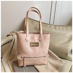 Detail view of pink tote bag showing pleated leather texture and decorative metal plaque