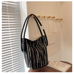 Detail of colorful woven stripes and black leather handles on a stylish bucket bag