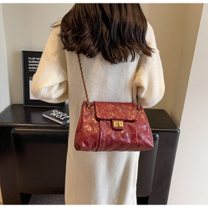 Detail of red quilted leather crossbody bag with gold chain strap and vintage clasp